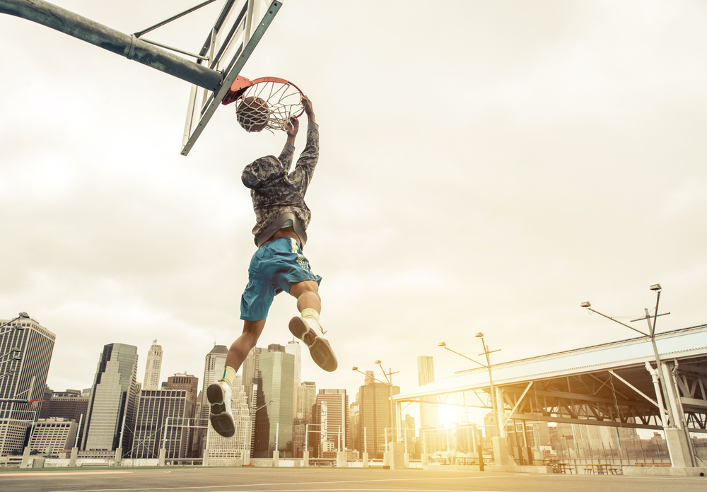 Basketball street player making a rear slam dunk
