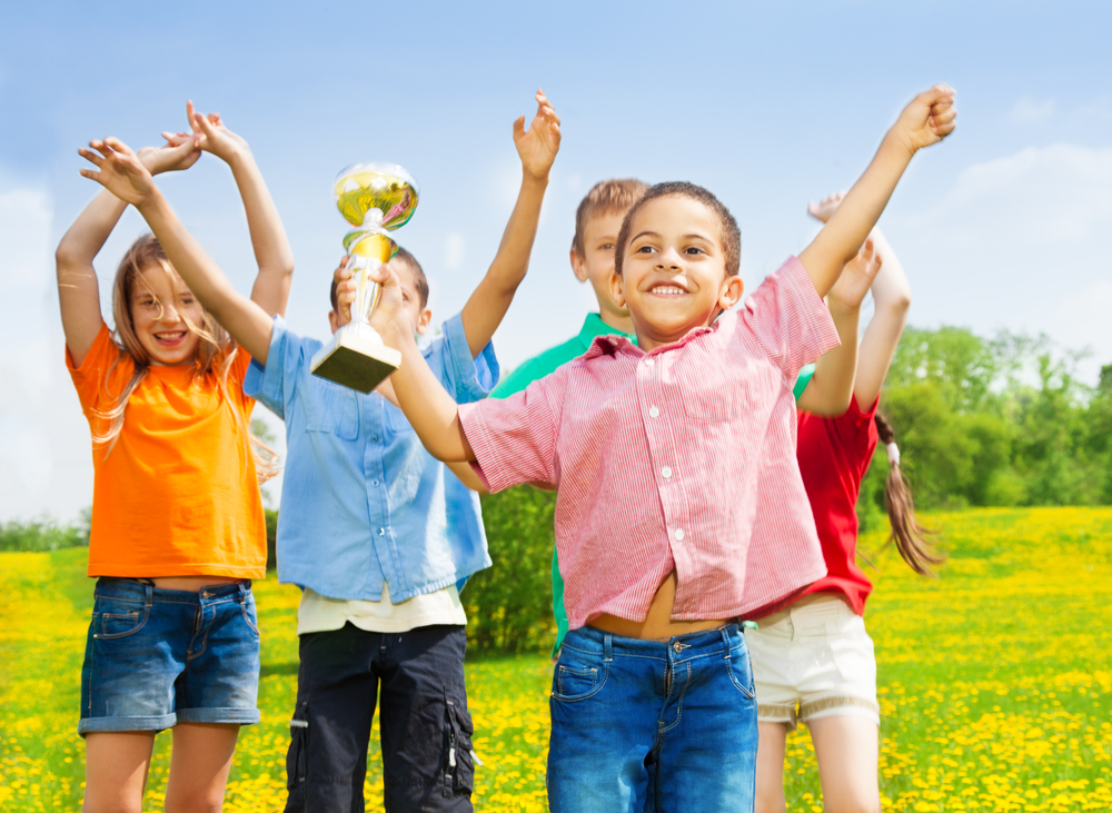 Black little boy standing with cup as his team wins