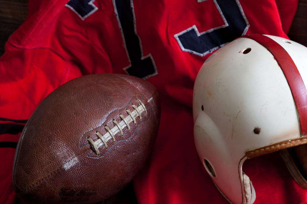 A group of vintage, antique American football equipment including a jersey, football and a helmet