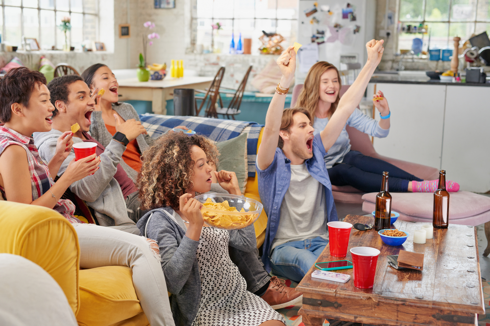 Diverse mix of friends sports fans watching winning football match on TV