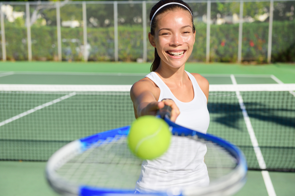 How Championship Rings Can Motivate Teams to Victory. Tennis player portrait. Woman showing tennis ball and racket smiling happy. Female athlete inviting you to play tennis. Healthy active sport and fitness lifestyle concept outdoor.