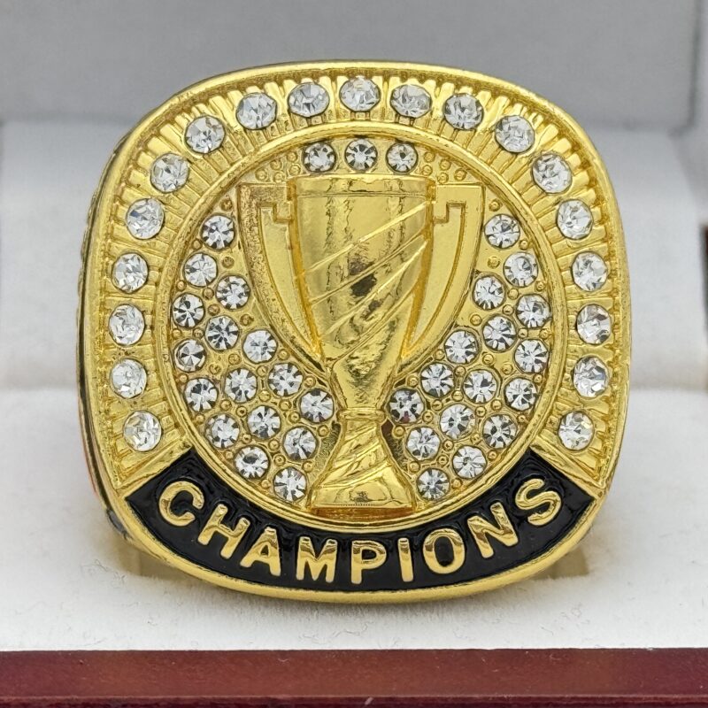 gold champions ring with a golden trophy in the center and silver gems