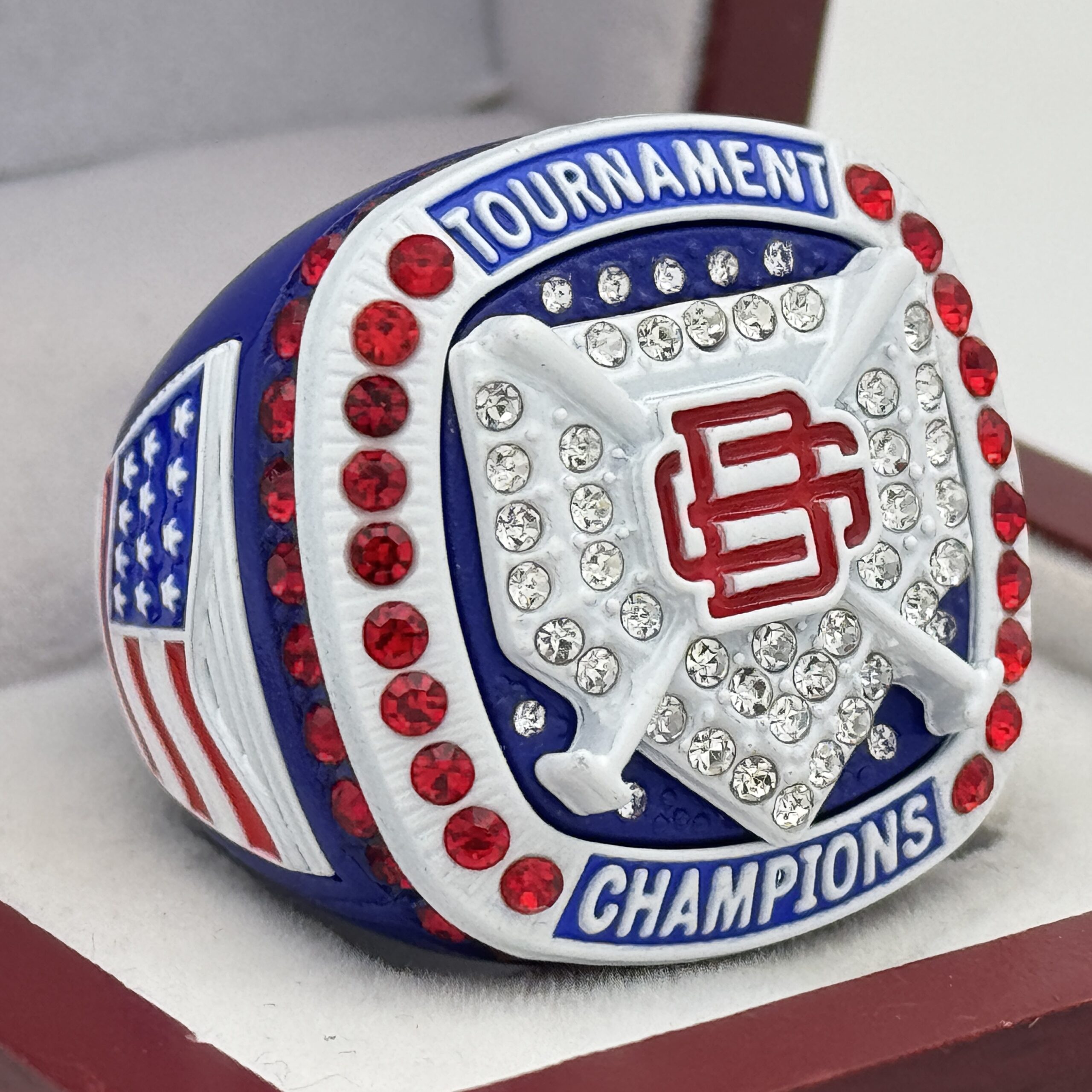 red white and blue tournament champions ring wiith baseball bats and a home plate